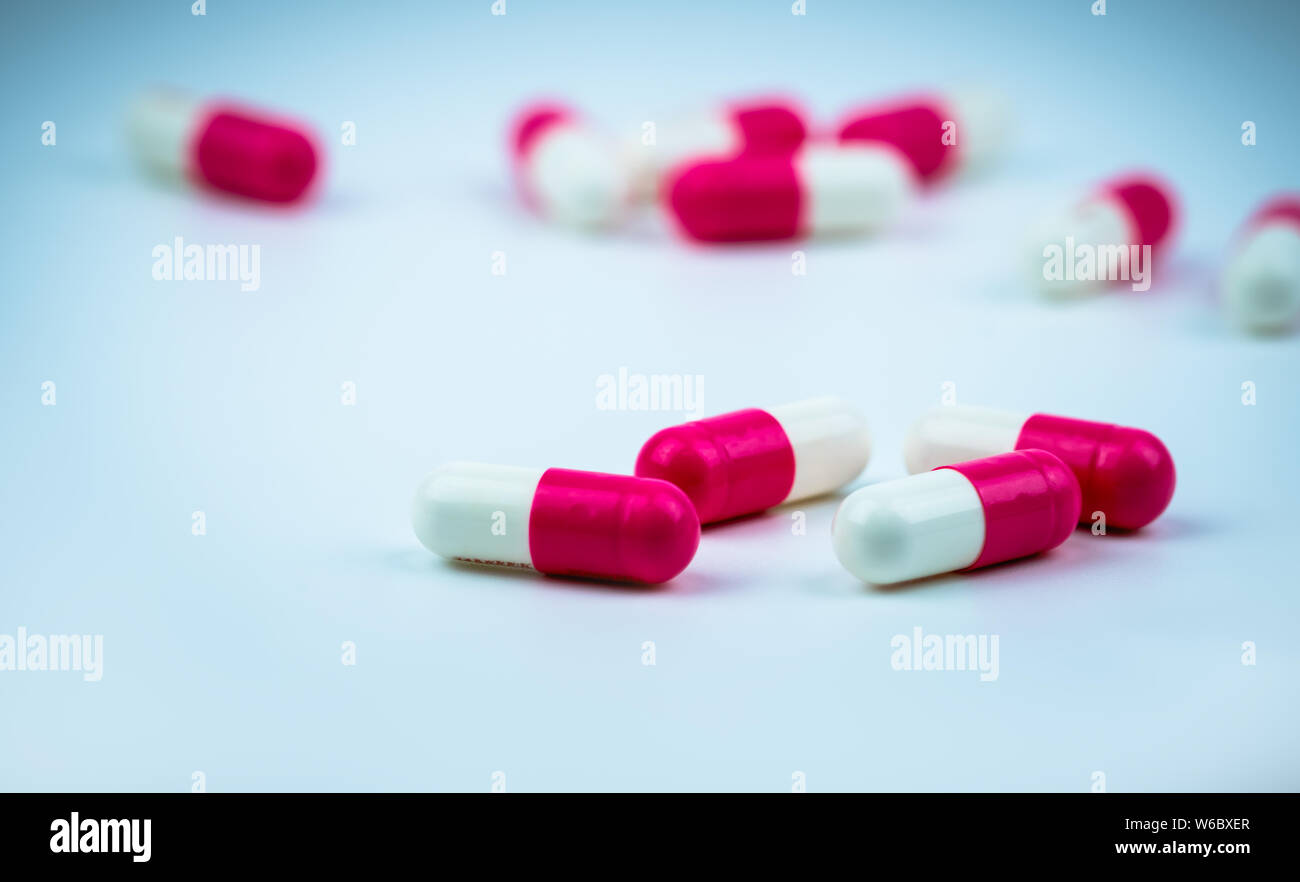 Pinkwhite capsule pill on blurred capsule background. Antibiotic drug