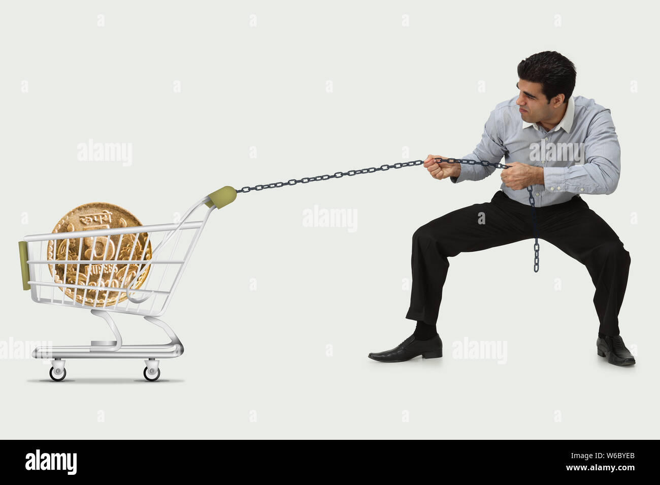 Man hauling Indian five rupee coin in a shopping cart Stock Photo