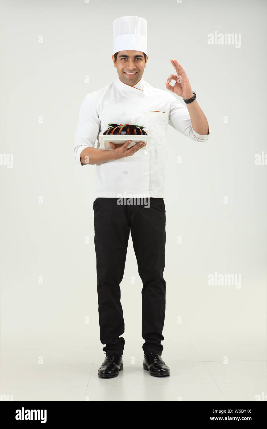 Chef holding a cake and showing ok sign Stock Photo