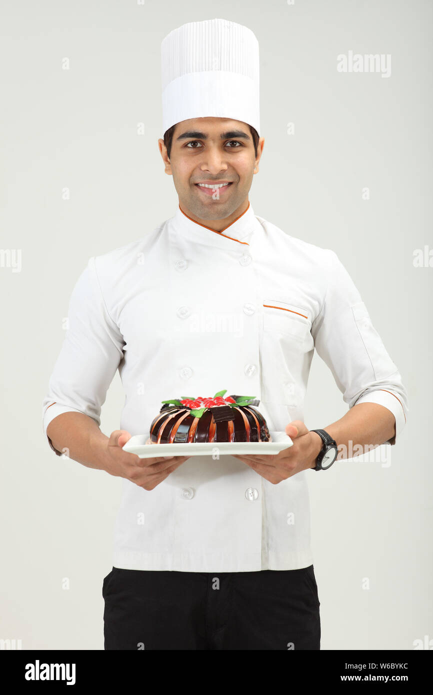 Mixed Race female pastry chef holding cake Stock Photo - Alamy