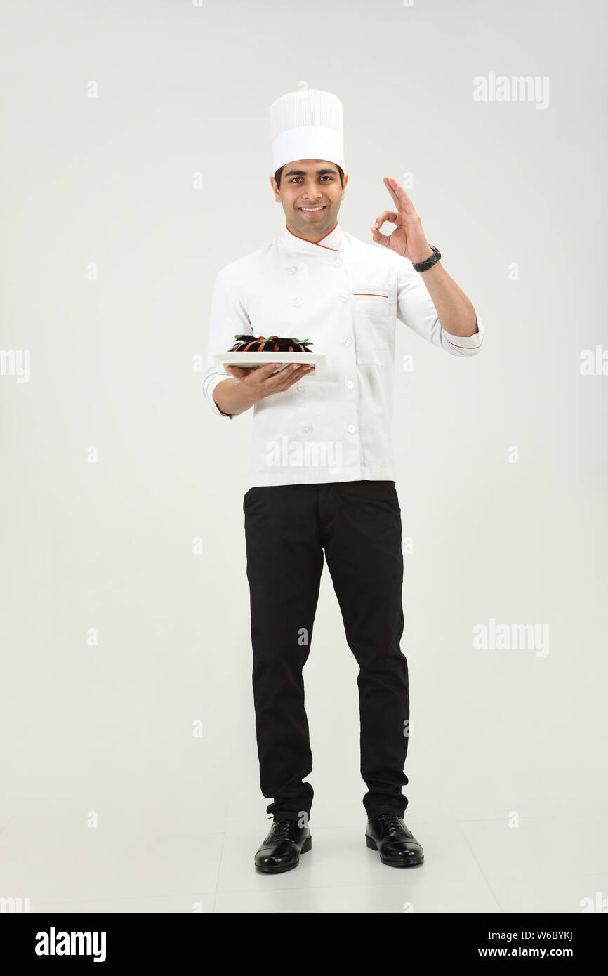 Chef holding a cake and showing ok sign Stock Photo