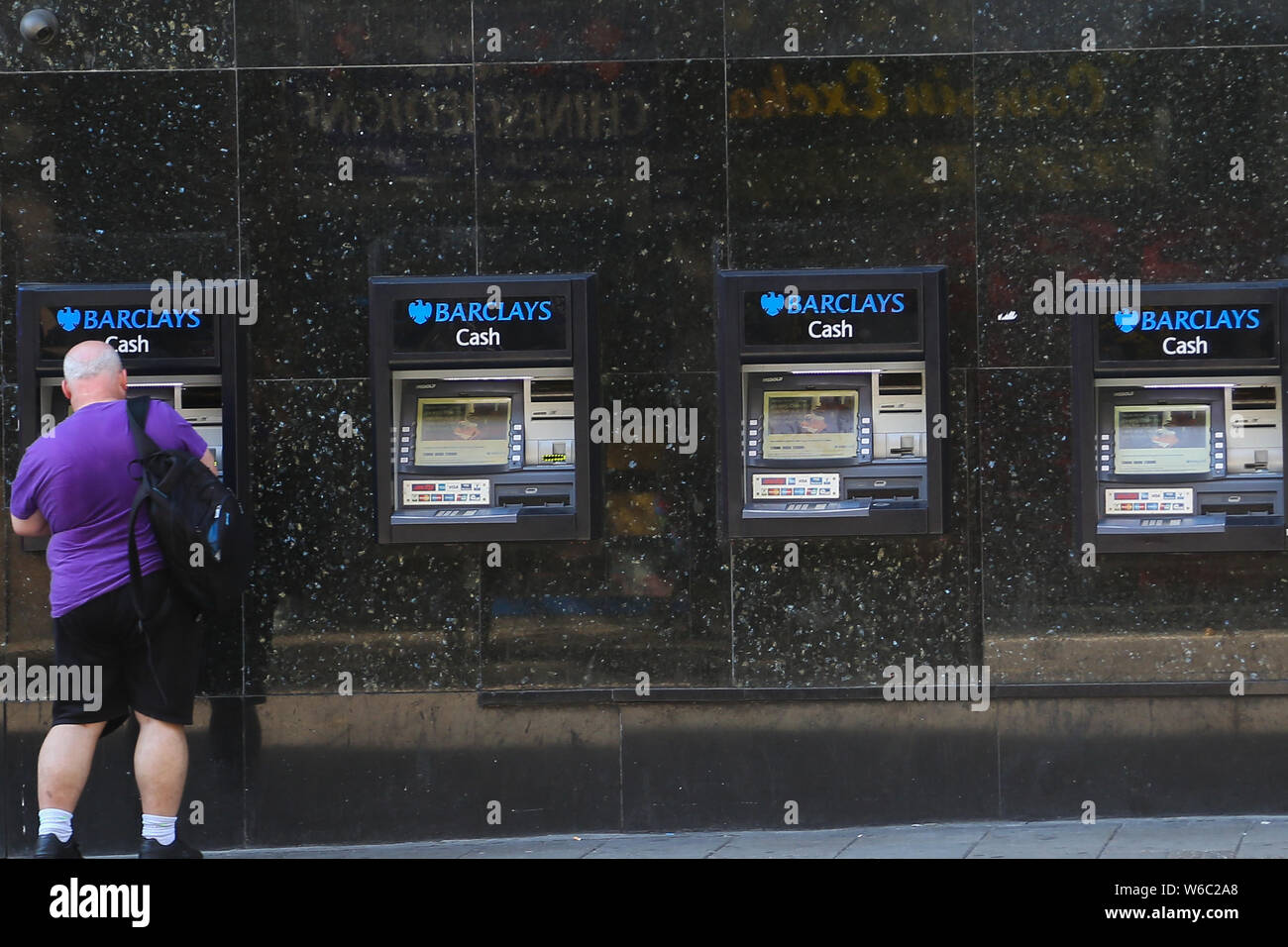 A Man Uses The Atm Machines Outside Barclays Bank In London Stock