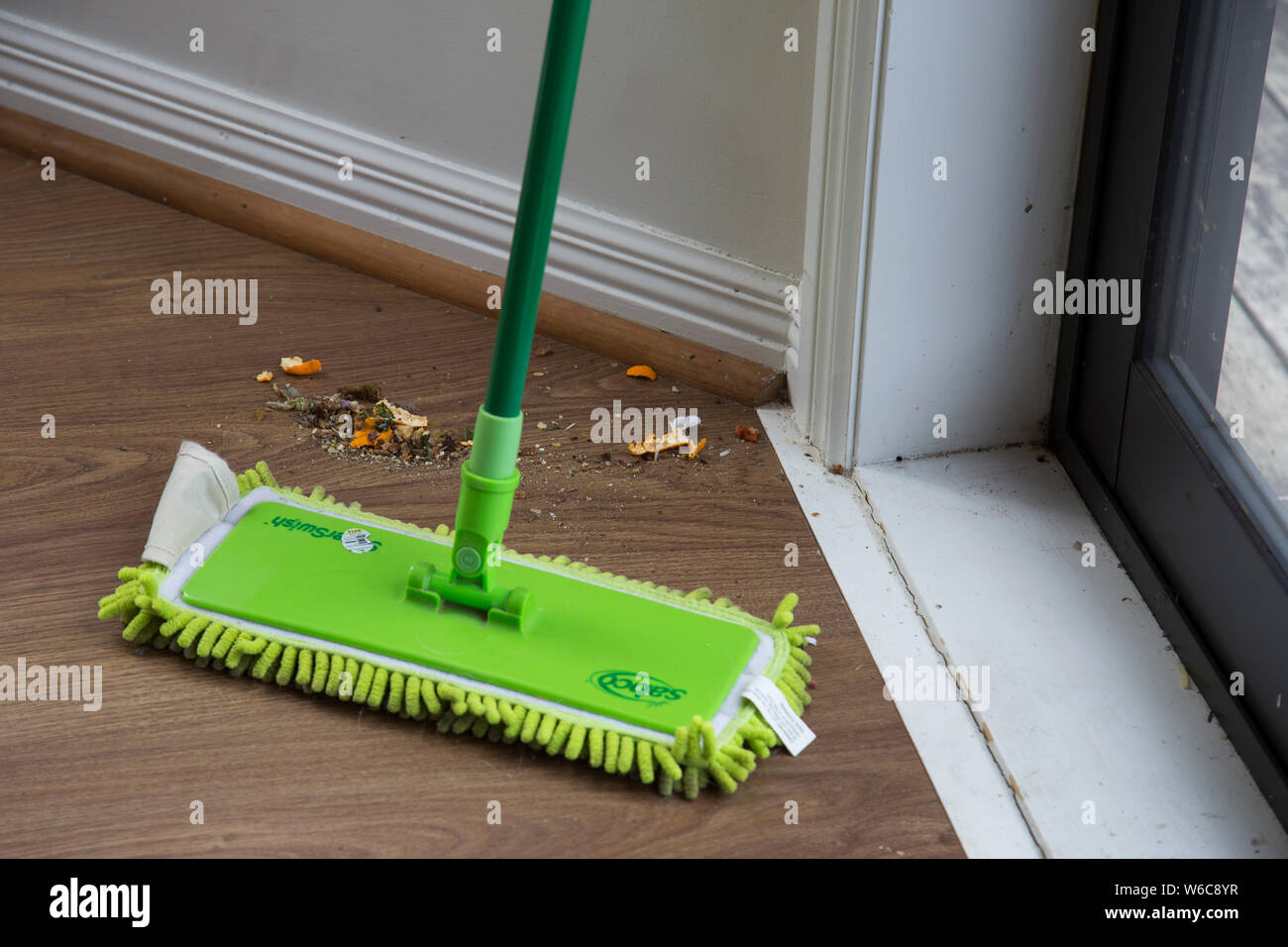Messy wooden laminate flooring after been swept with a Sabco mop. This is  the mess the kids have made after eating lunch. Floor is brown, mop is  green Stock Photo - Alamy