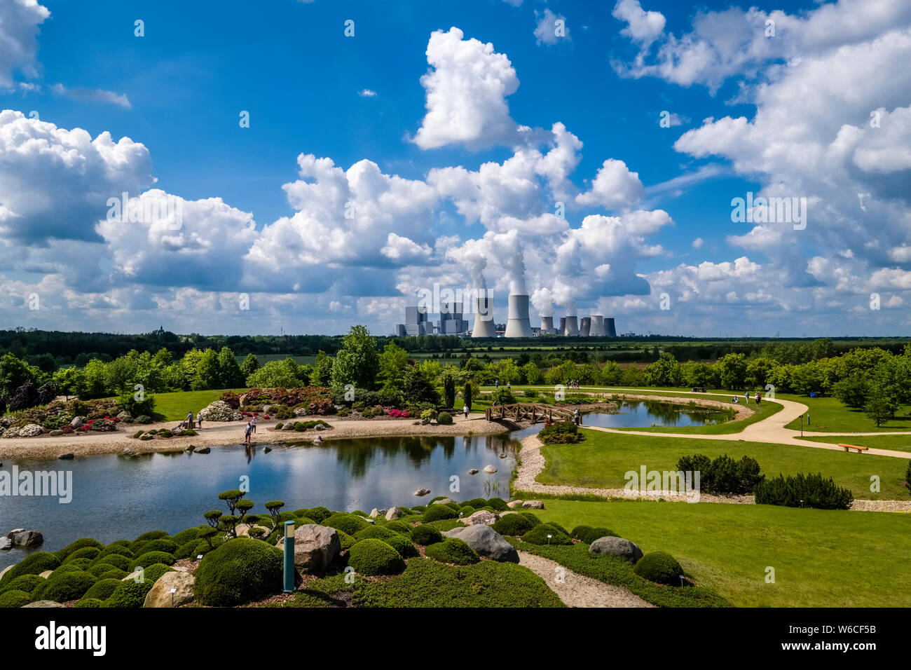The buildings and steaming cooling towers of a coal-fired power plant behind a landscape park Stock Photo