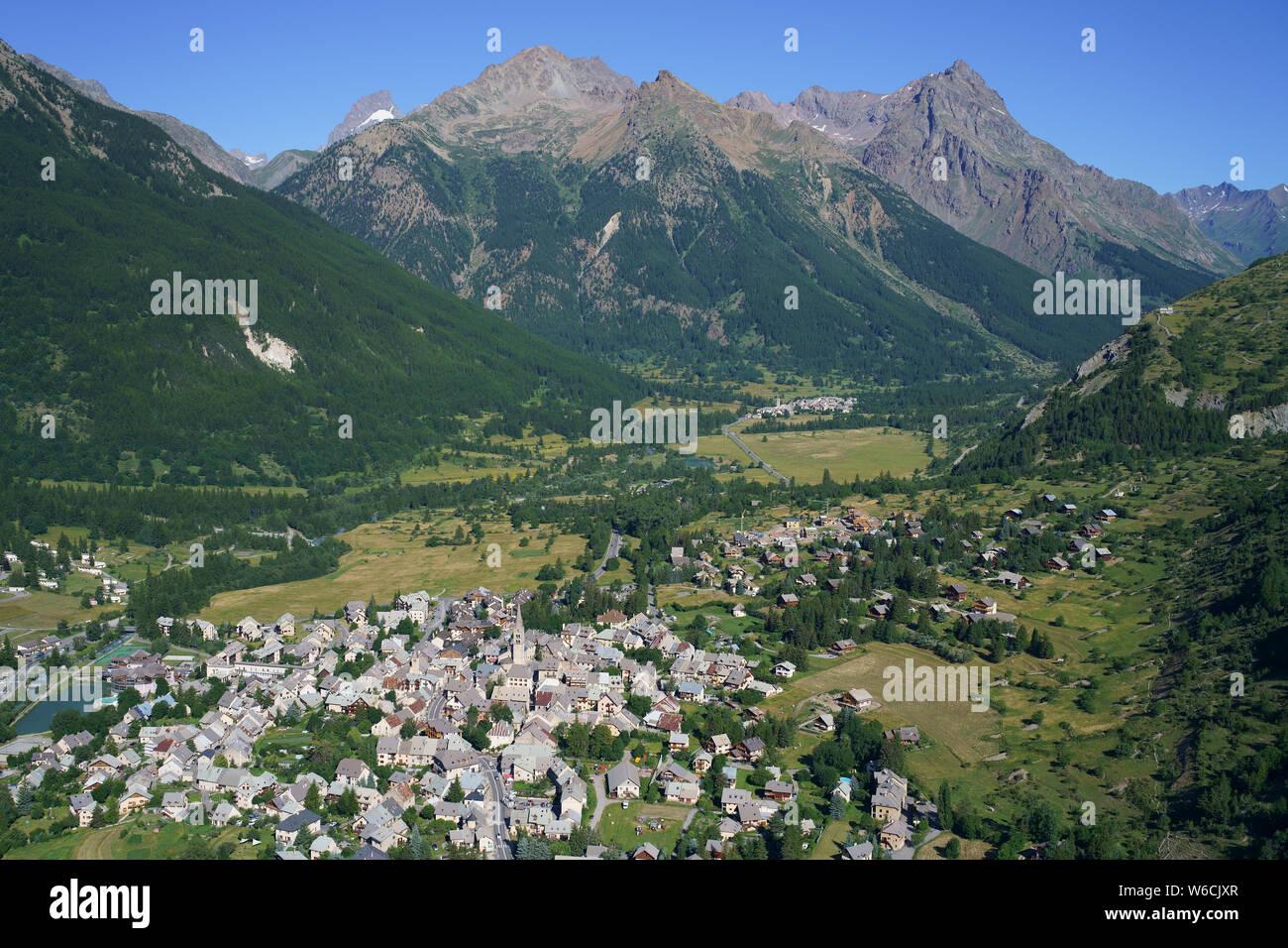 AERIAL VIEW. La Guisane Valley with the town of le Monêtier-les-Bains and the lofty peaks of Les Écrins Massif. Hautes-Alpes, France. Stock Photo