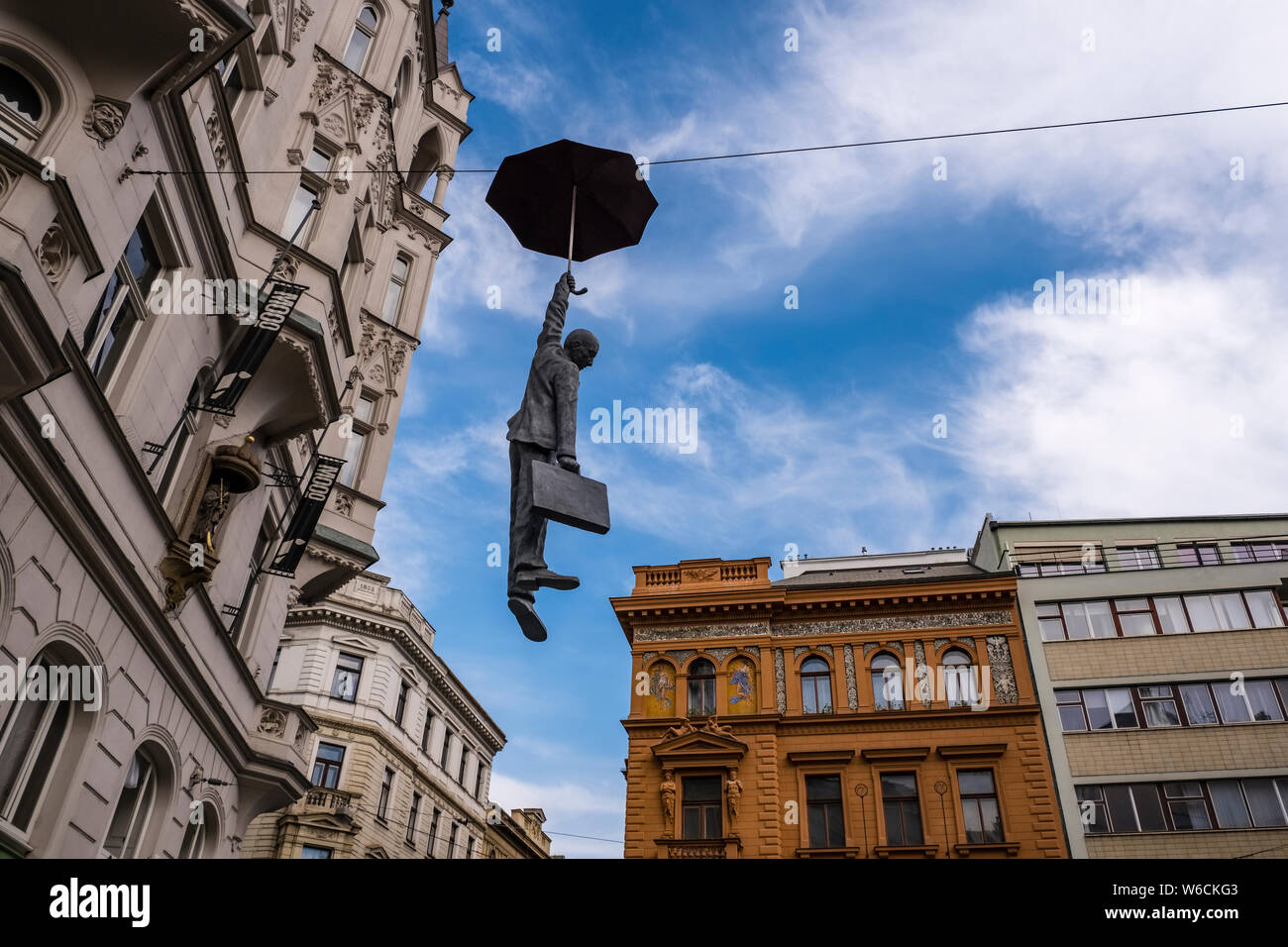 Streetart, the sculpture of a man with an umbrella floating in the air between buildings Stock Photo