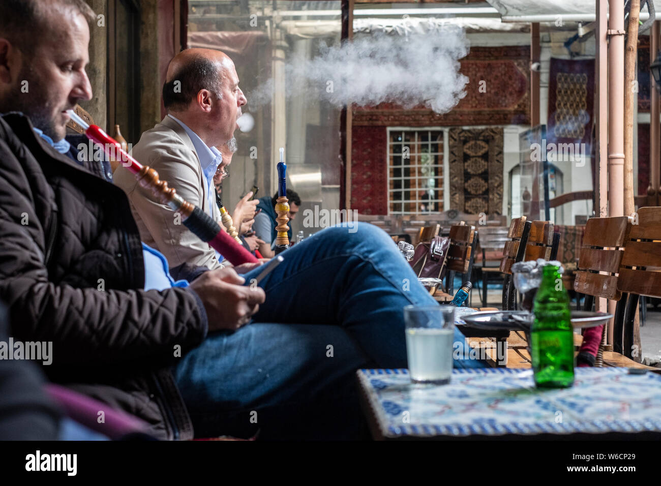 Three Turkish men smoking hookahs with shisha in a specialty cafe in central Istanbul, Turkey Stock Photo