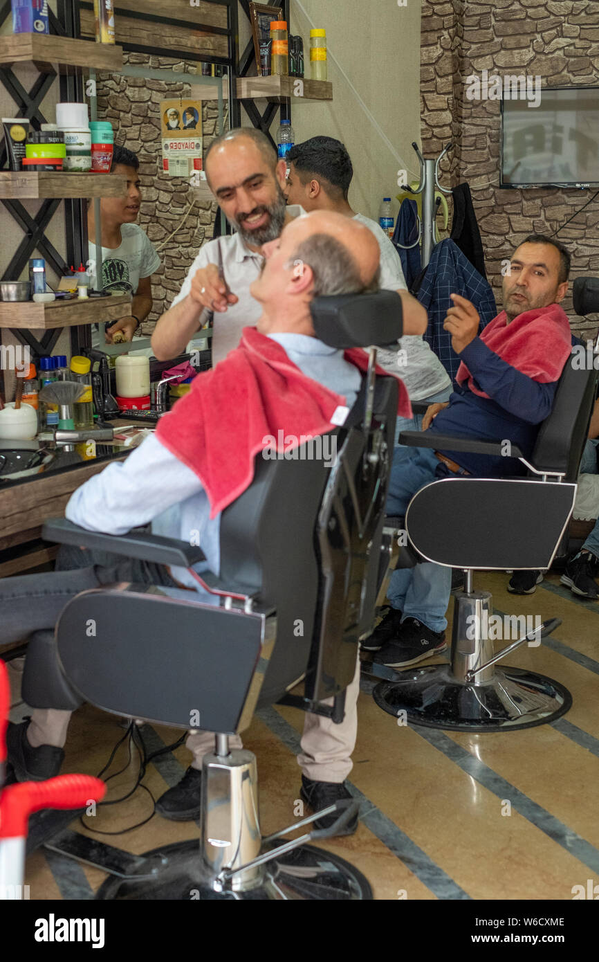 Barbers give their clients haircuts and shaves in a barber shop in central Istanbul, Turkey Stock Photo