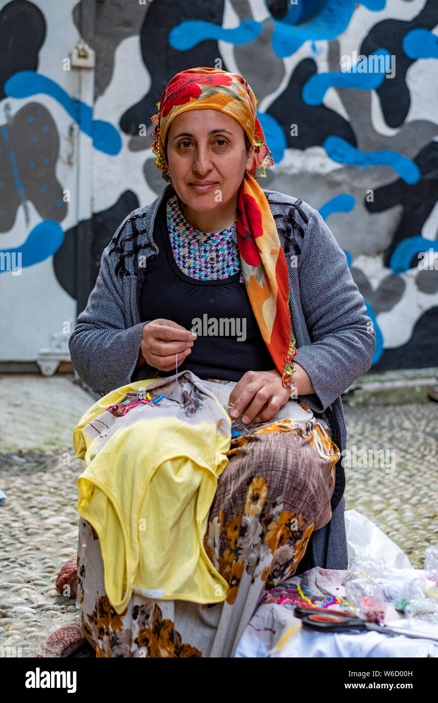 Portrait of a Turkish woman in a headscarf sewing on the street in front of her home in Istanbul, Turkey Stock Photo