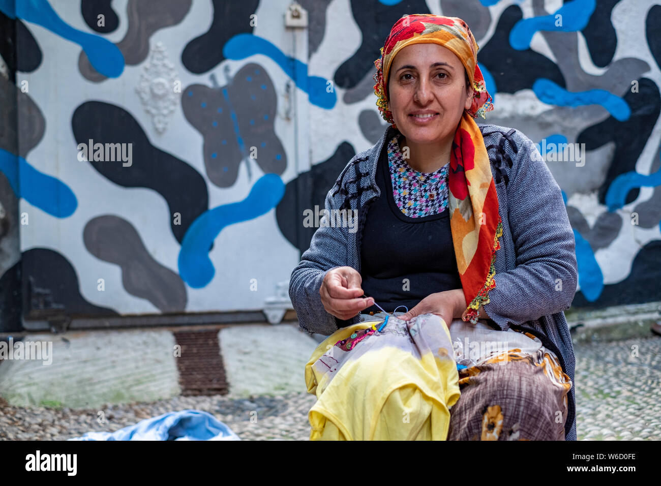 Portrait of a Turkish woman in a headscarf sewing on the street in front of her home in Istanbul, Turkey Stock Photo