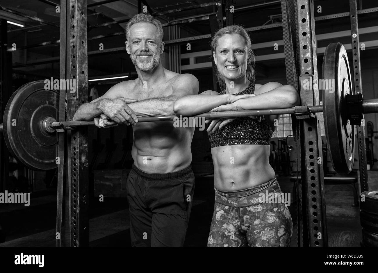 Portrait of a middle aged beautiful and athletic couple who is doing a fitness training together and having fun. Strong man and woman on the barbel. Stock Photo