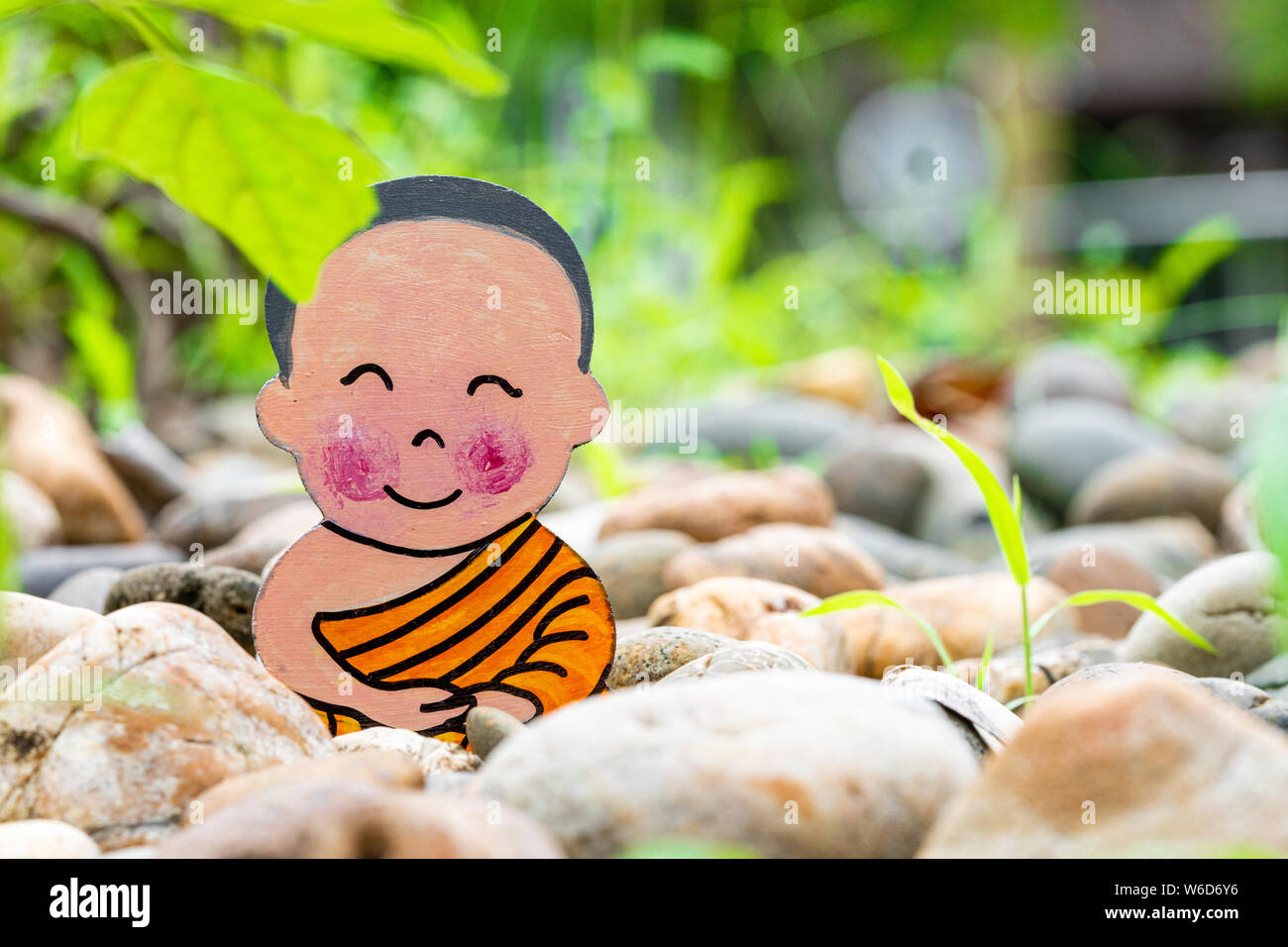 Little boy Buddhist, little Buddha, sitting on the sand on stones ...