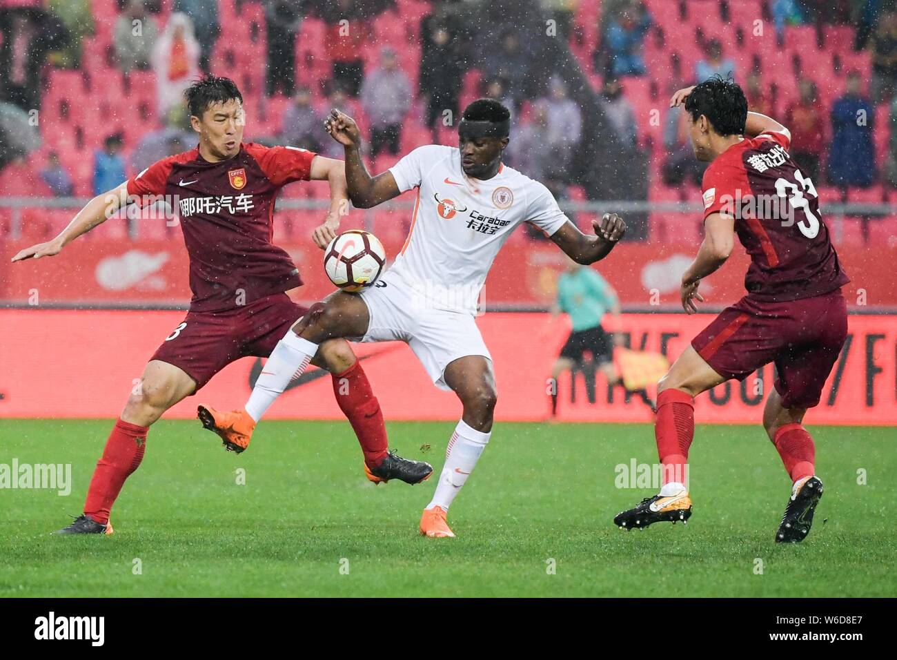Cameroonian football player Benjamin Moukandjo, center, of Beijing Renhe kicks the ball to make a pass against players of Hebei China Fortune in their Stock Photo