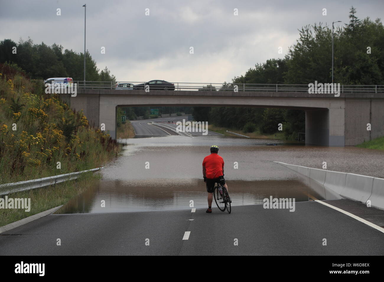 A bike rider comes to a halt as flood water blocks a road on the A555 near Handforth, Cheshire, where a major incident was declared late on Wednesday after heavy rainfall caused severe flooding. Stock Photo