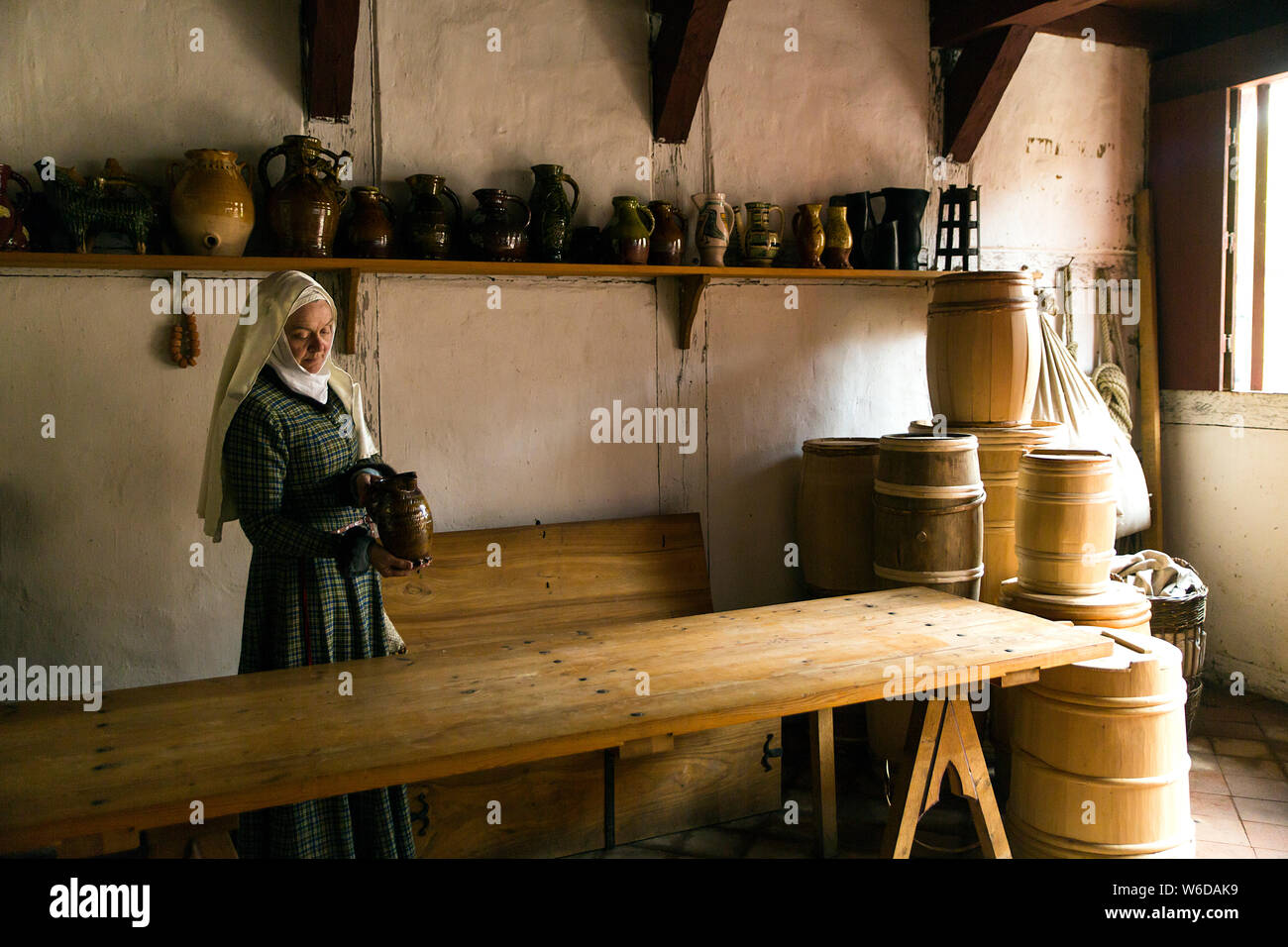 A woman in a tavern at the outdoor Medieval Centre in Nykøbing Falster, Denmark.  The Medieval Centre is built around the village Sundkøbing at a fjord as it was around the year 1400. Houses are authentically designed and built with the people who populate the village, men, women, children, peasants, craftsmen, warriors and knights etc dressing and work as they would back in 1400.  Canons and large trebuchets can be seen firing missiles, knights in armour on horseback competing with lances and swords, dyers colouring textiles with plants and in the convent garden nuns grow medicinal herbs. Stock Photo