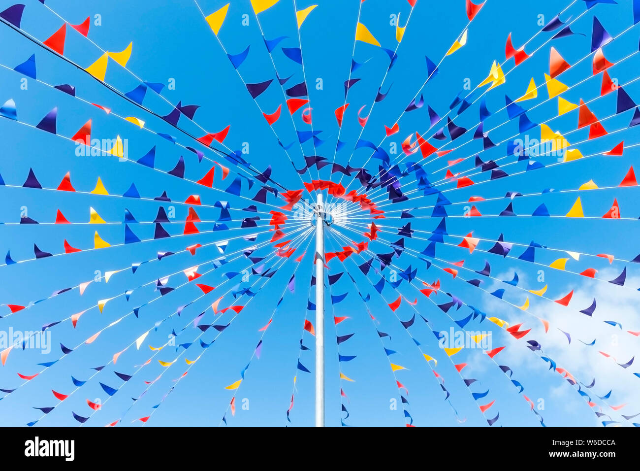 Colourful bunting attached to a pole seen against a bright blue sky. Stock Photo