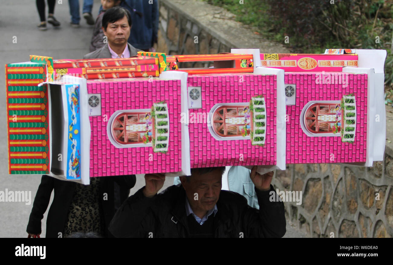 --FILE--A Chinese man carries a paper villa of burning offerings for deceased relatives during the Qingming Festival, or the Tomb Sweeping Day, in Wuh Stock Photo