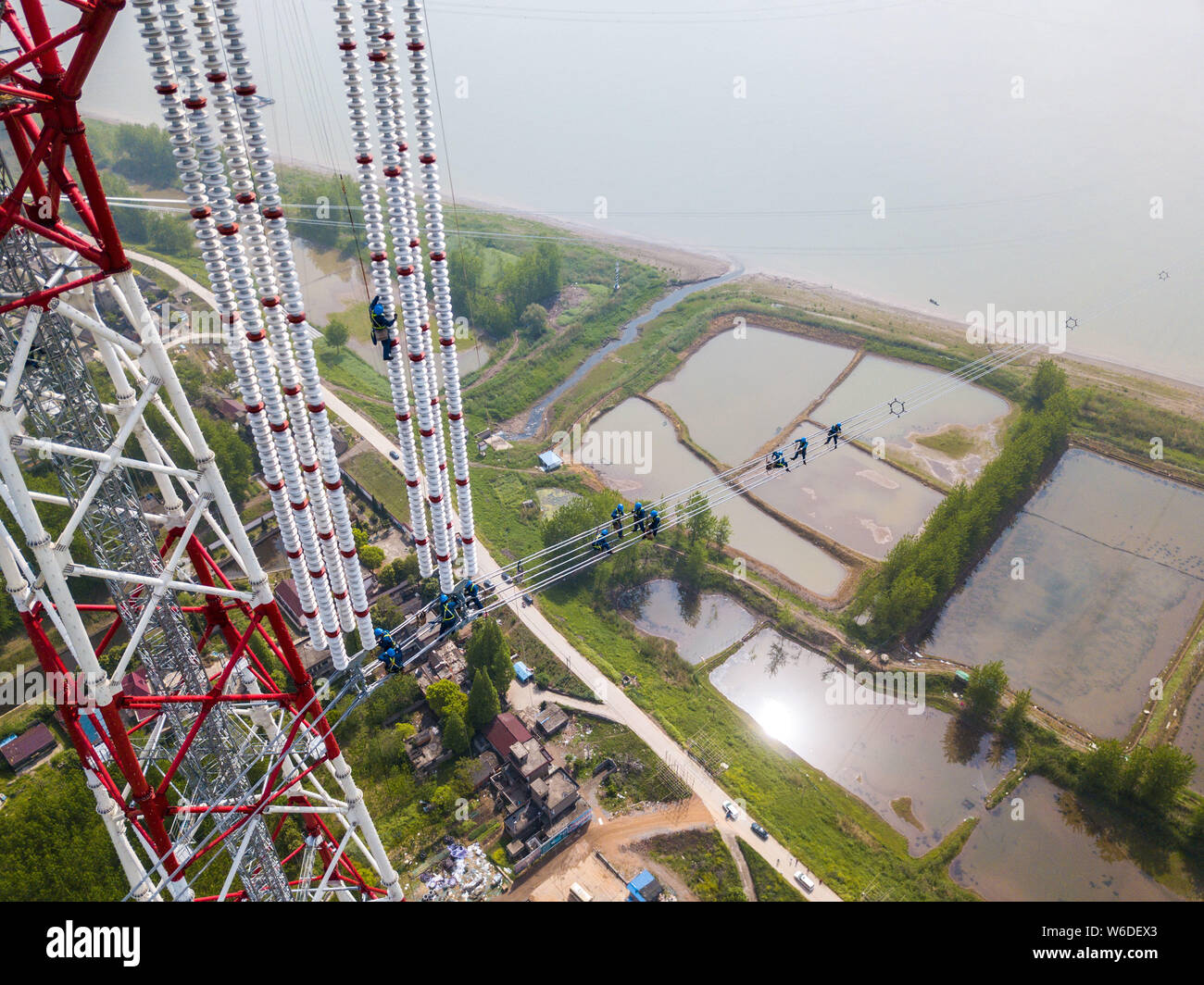 Chinese workers labor at the construction site of the Changji-Guquan UHVDC (ultra-high voltage direct current) transmission link along the Yangtze Riv Stock Photo