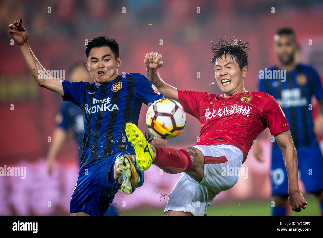 South Korean football player Kim Young-gwon of Guangzhou Evergrande Taobao, right, kicks the ball to make a pass against Huang Zichang of Jiangsu Suni Stock Photo