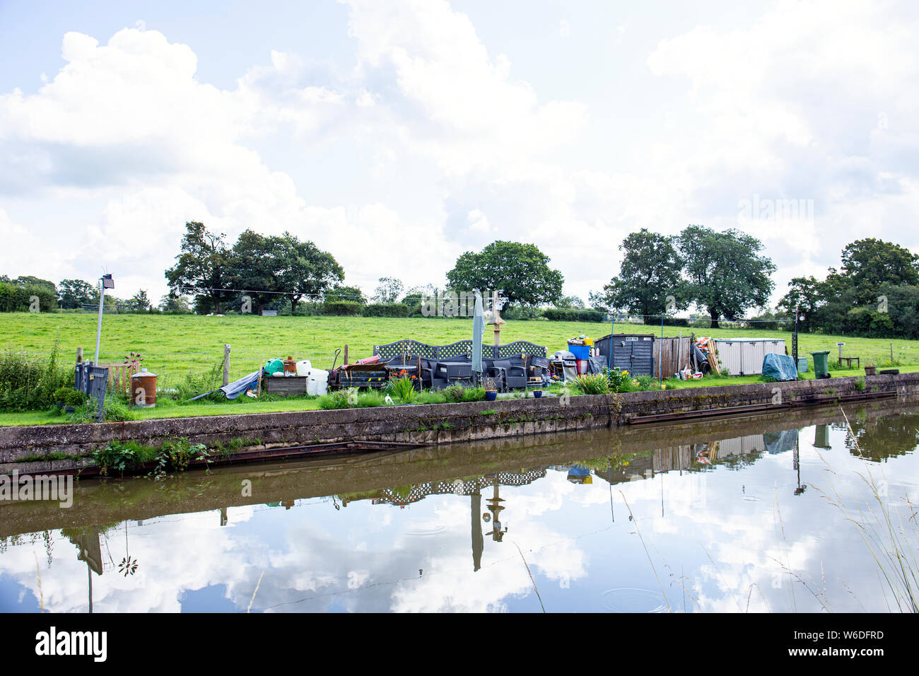 Reserved mooring space for an narrow boat called Moor Time with private garden, and mess, on the Trent and Mersey Canal in Cheshire UK Stock Photo