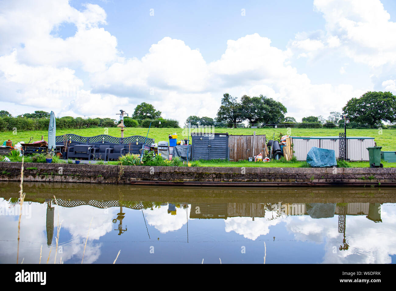 Reserved mooring space for an narrow boat called Moor Time with private garden, and mess, on the Trent and Mersey Canal in Cheshire UK Stock Photo