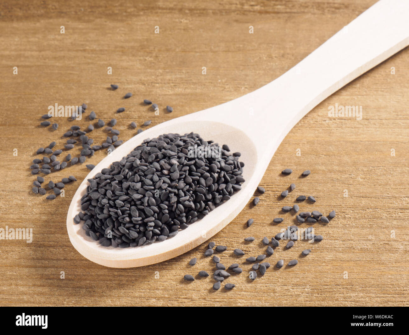 Black sesame (Sesamum indicum) in a spoon on a wooden background diagonally Stock Photo