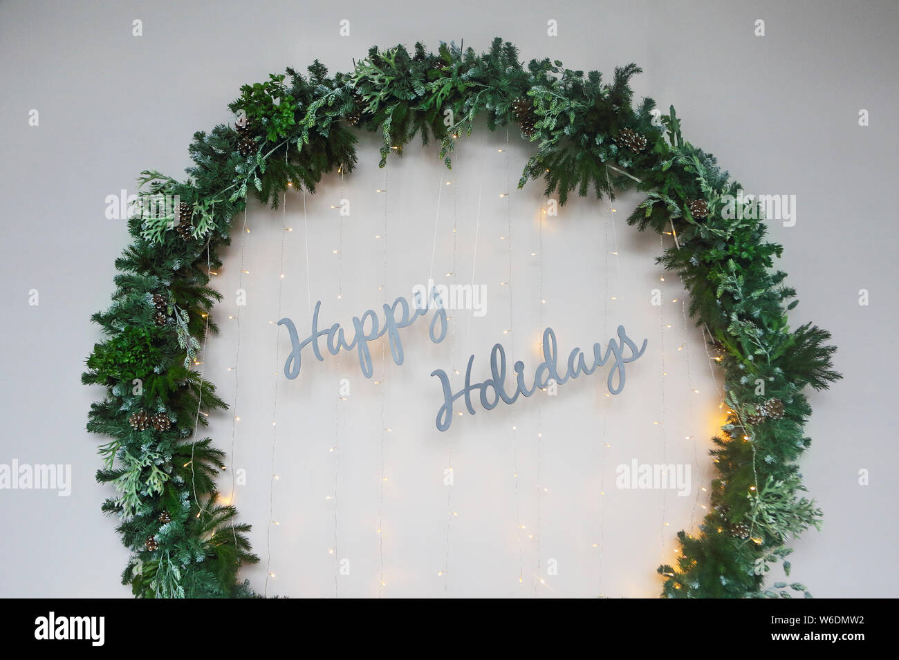 Big Christmas wreath by the wall with sign Happy Holidays. Close up Stock Photo