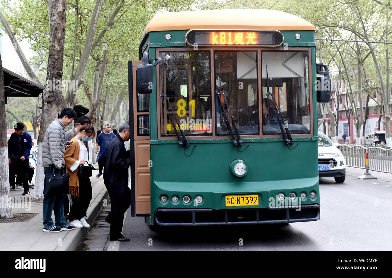 Passengers get on a trolley-shaped bus, locally known as a dangdangche ...