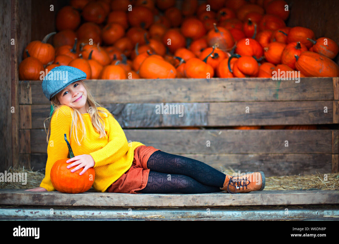 Happy little girl at the autumn pumpkin patch background. Having fun ...