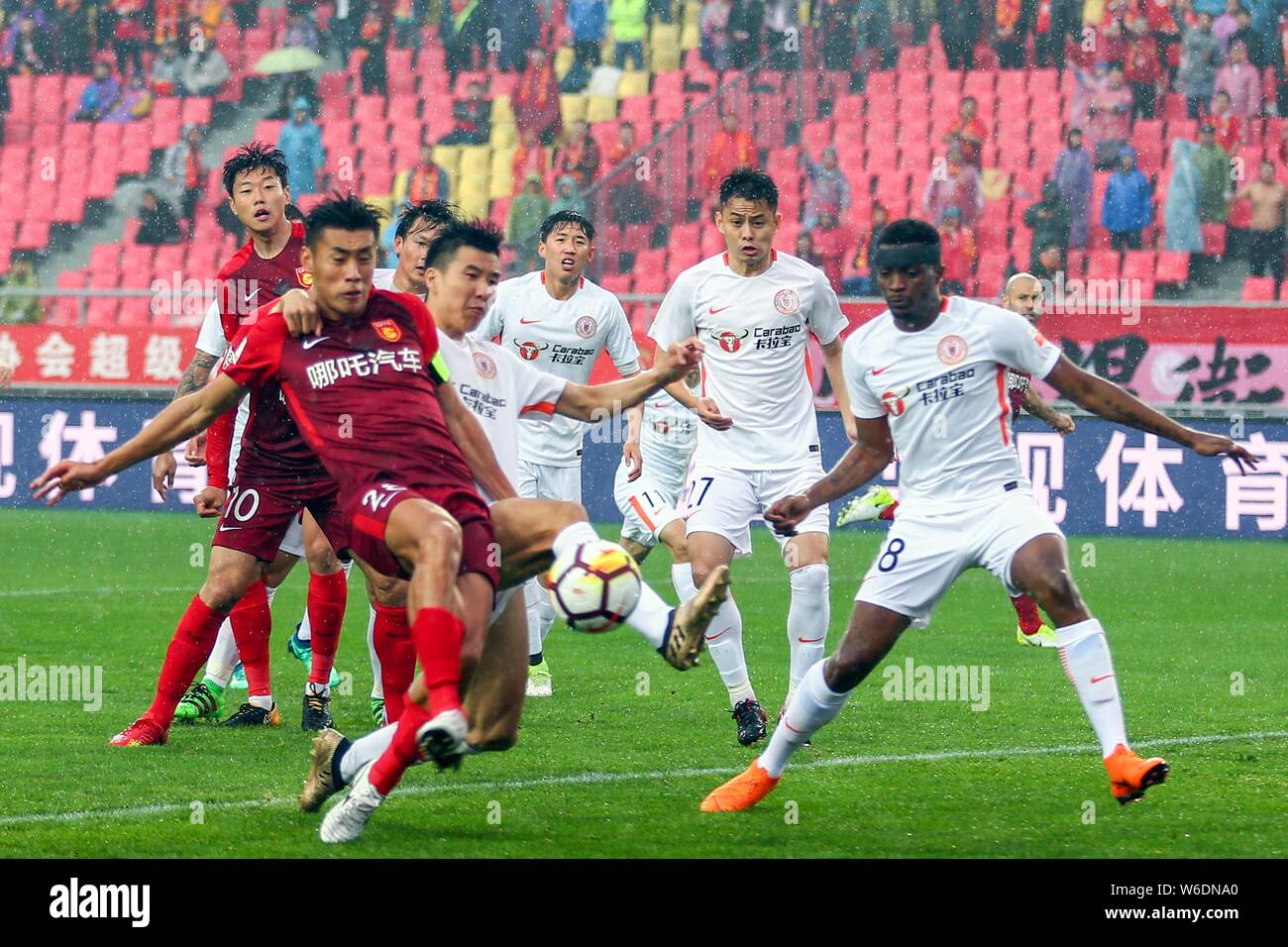Cameroonian football player Benjamin Moukandjo, right, of Beijing Renhe challenges players of Hebei China Fortune in their seventh round match during Stock Photo
