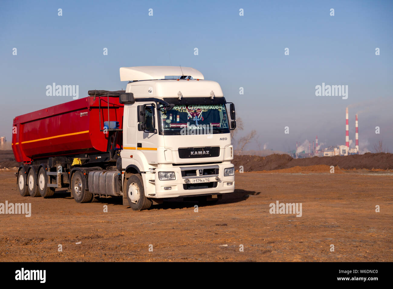 Russia Kemerovo 2019-04-09 red and white model Kamaz on field on background of the city landscape and factory pipes. Concept truck on Rally Dakar in d Stock Photo