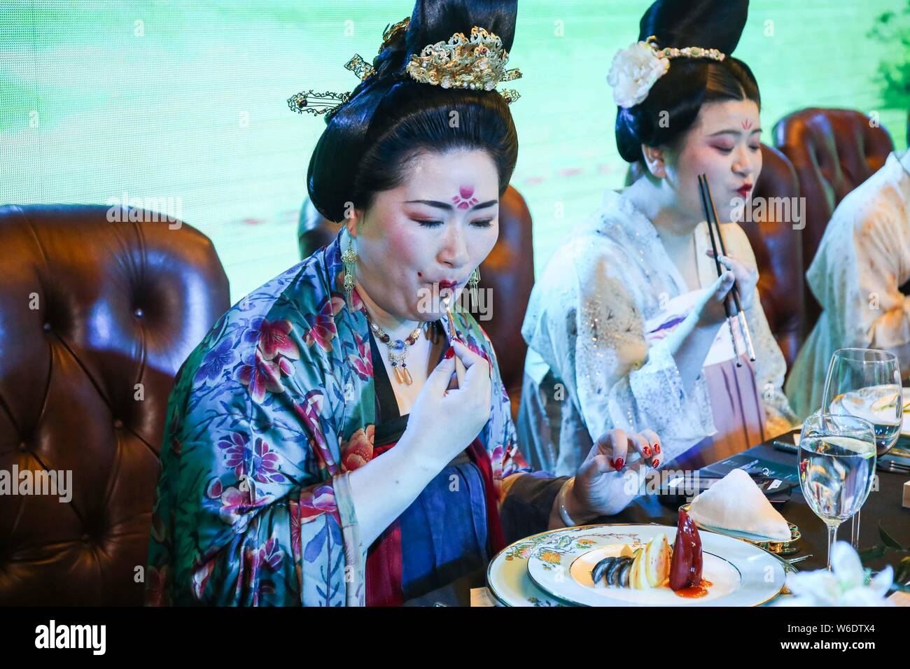 Chinese women dressed in Han Chinese clothing that imitates the style of clothes worn by women during the Tang Dynasty (618-907) eat at a meat feast a Stock Photo