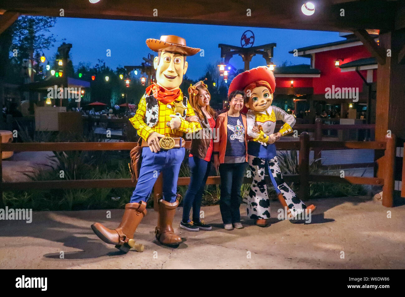 Visitors pose with sculptures of Sheriff Woody and Jessie, both characters of Pixar's animated film 'Toy Story', at the seventh themed land, Disney Pi Stock Photo