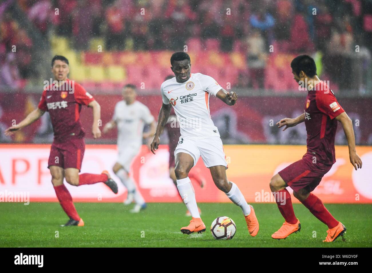 Cameroonian football player Benjamin Moukandjo, center, of Beijing Renhe kicks the ball to make a pass against players of Hebei China Fortune in their Stock Photo