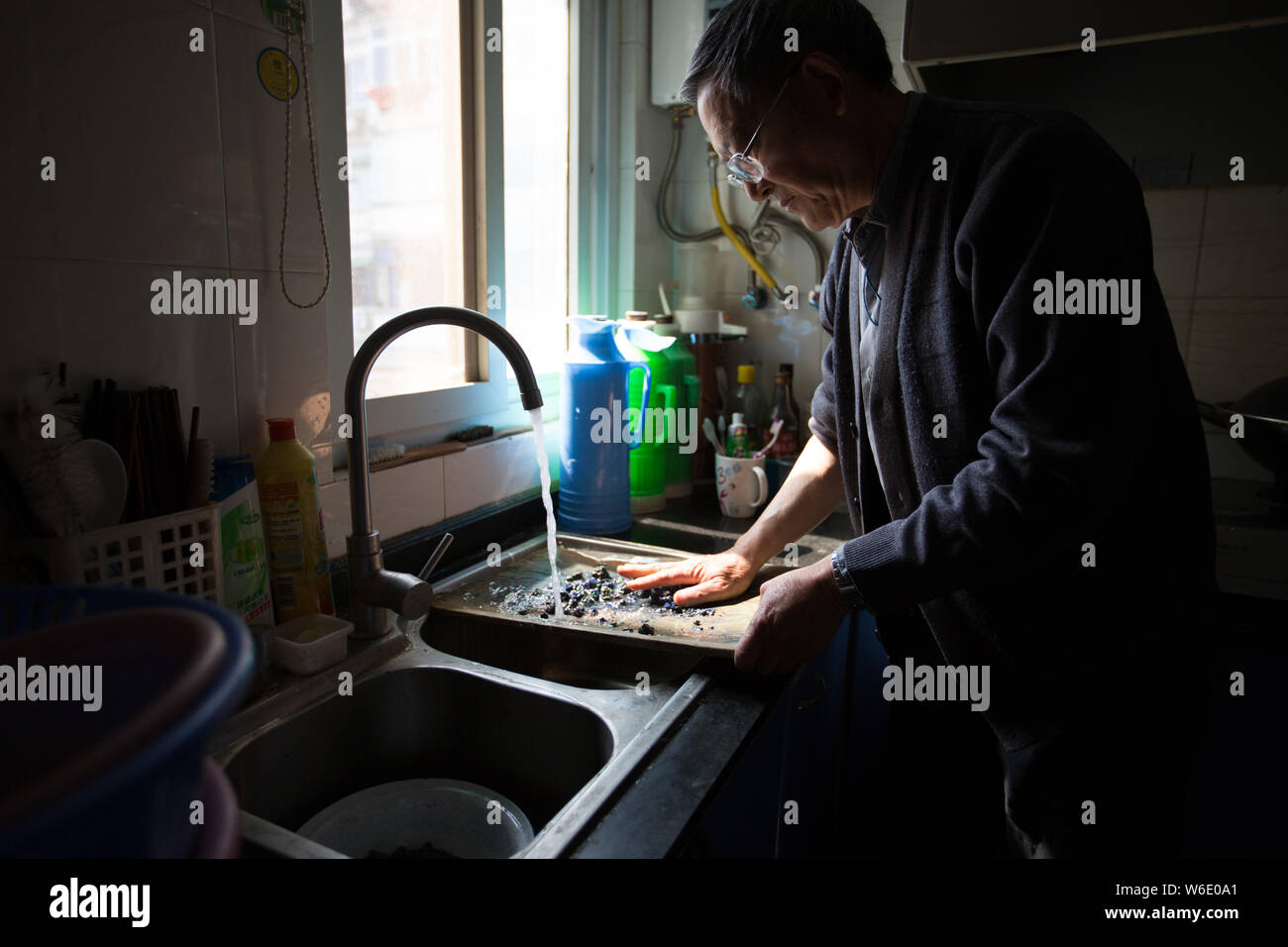 --FILE--74-year-old Chinese craftsman Qiu Qingnian washes natural minerals for making color pigments at his old apartment in Suzhou city, east China's Stock Photo
