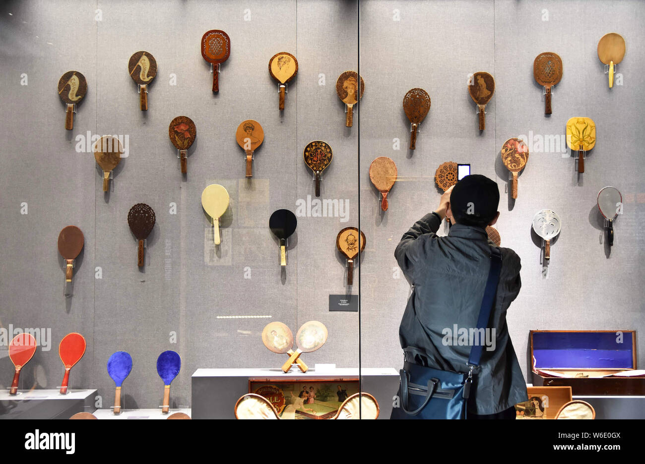 A visitor takes photos of a collection of table tennis rackets at the