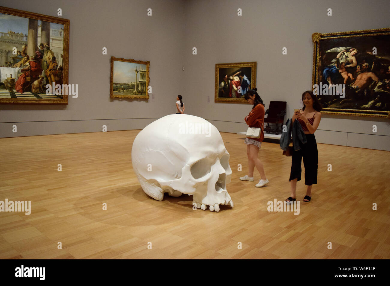 Visitors view 'Mass', an artwork of 100 larger-than-life skulls by Australian sculptor Ron Mueck, on display during the NGV Triennial art exhibition a Stock Photo