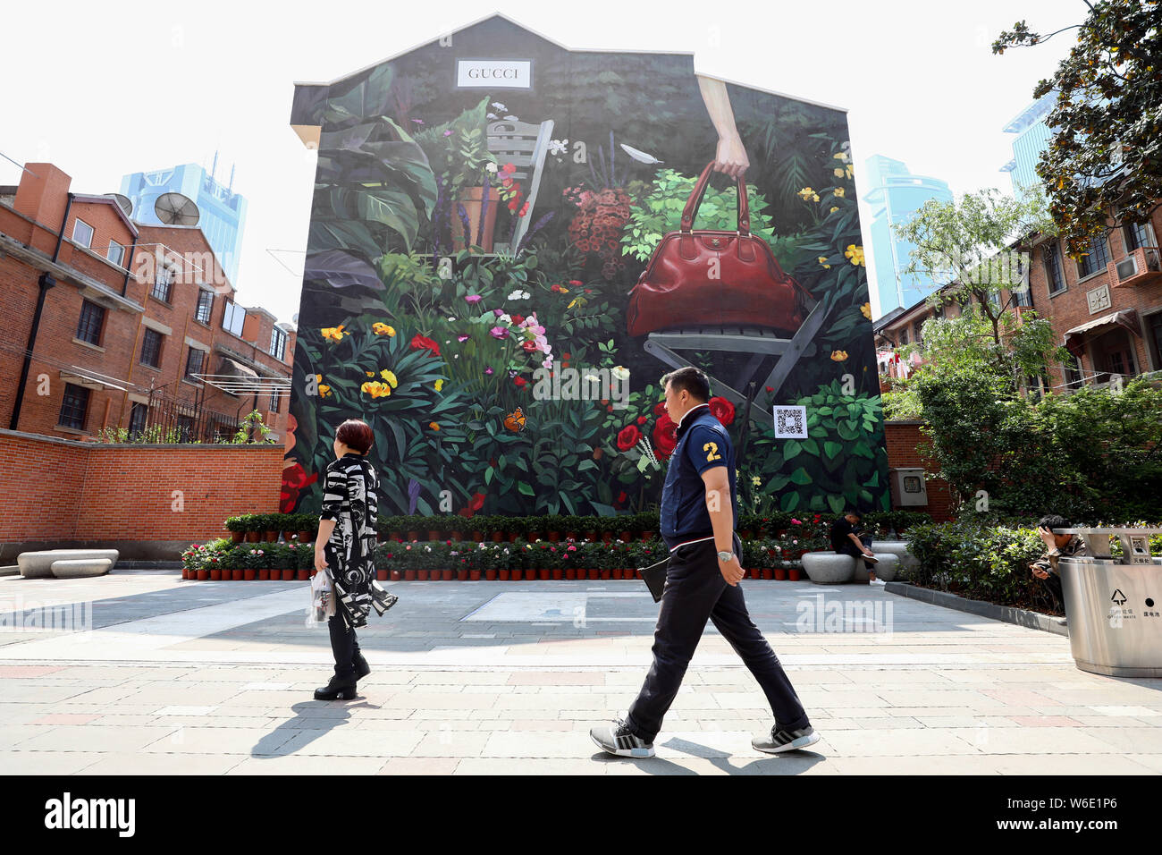 Pedestrians walk past Gucci's art wall painted by Spanish artist Ignasi Monreal on a road in Shanghai, China, 25 April 2018.   Gucci's new mural caugh Stock Photo