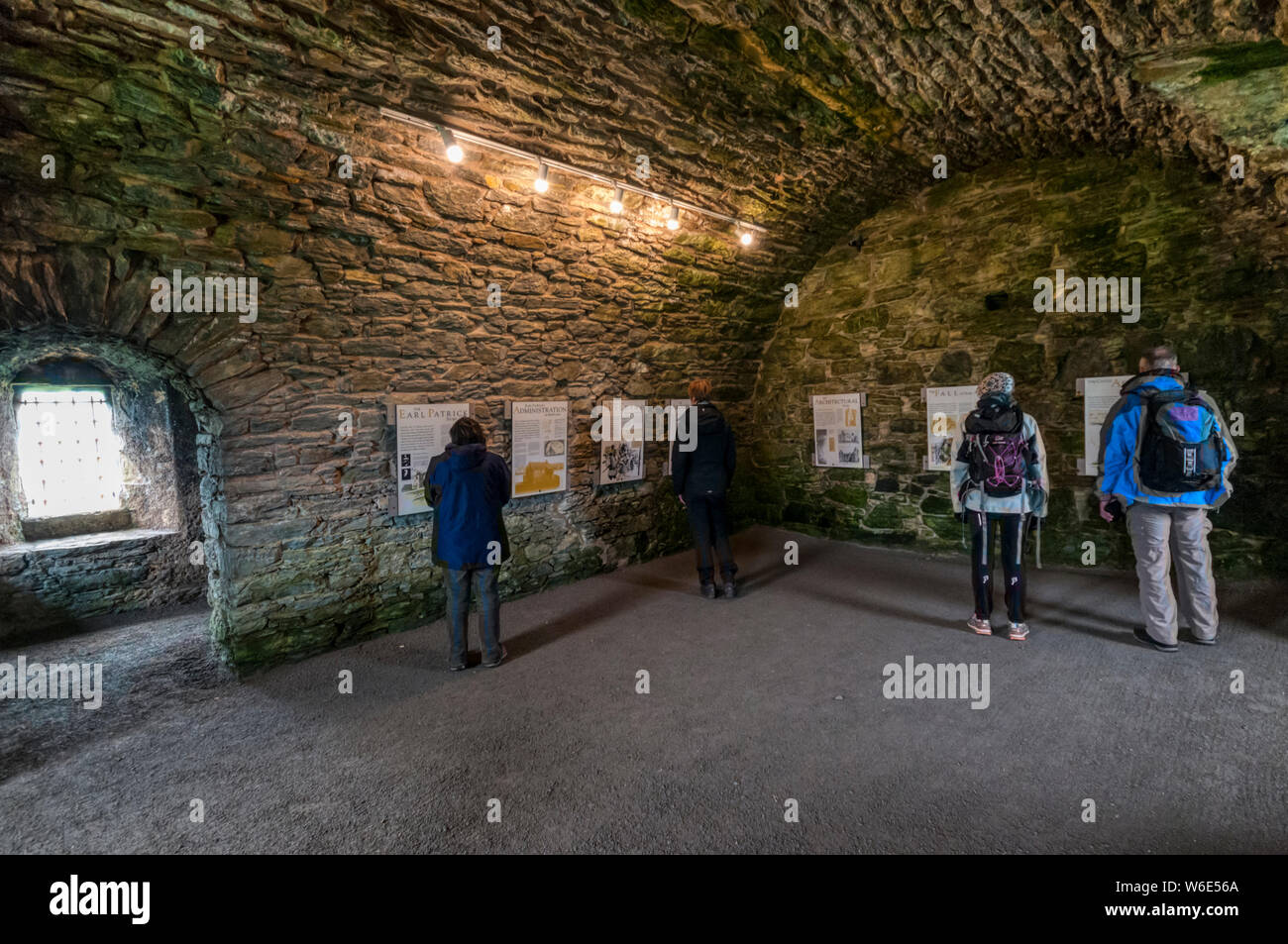 People reading interpretive panels about the history of Scalloway Castle, Shetland, in a storeroom of the castle. Stock Photo
