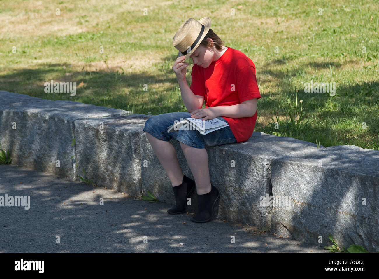 boy sitting on wall reading, Frauenau, Bayerischer Wald, Bavaria, Germany Stock Photo