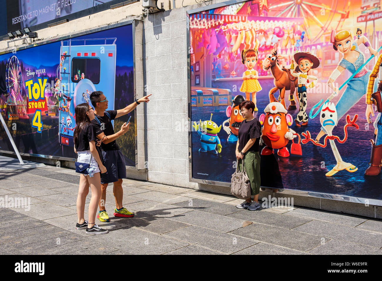 A woman poses next to an image of Potato Head, Bo Peep, Jessie, Squeeze Toy Aliens, Forky and Gabby Gabby during the Carnival.Toy Story 4 is celebrated with a themed carnival of different games and challenges at Hong Kong Harbour City. Stock Photo