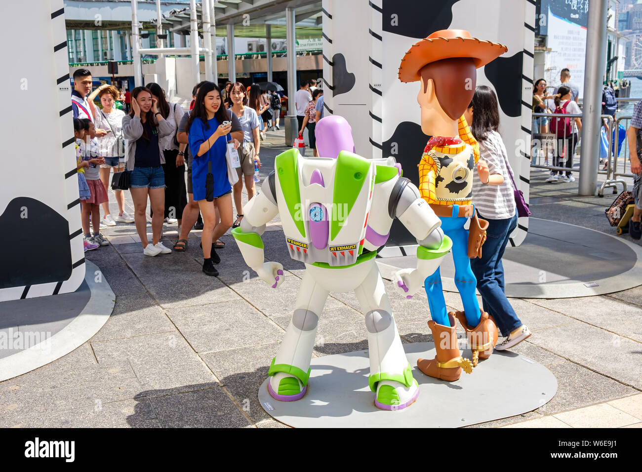 A woman posses next to replicas of Sheriff Woody and Buzz Lightyear during the Carnival.Toy Story 4 is celebrated with a themed carnival of different games and challenges at Hong Kong Harbour City. Stock Photo