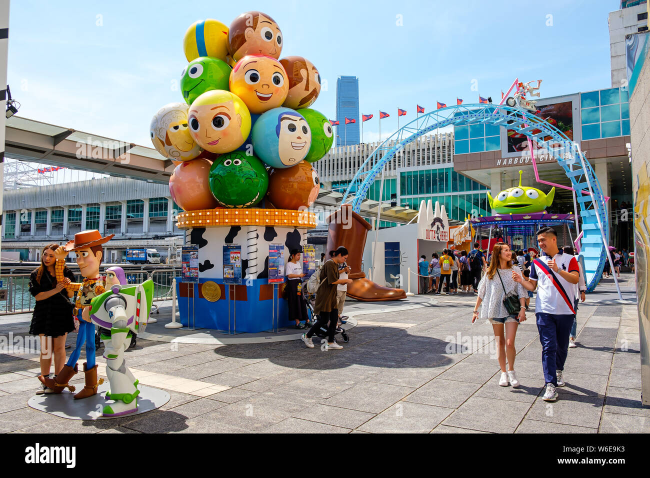 A woman posses next to replicas of Sheriff Woody and Buzz Lightyear during the Carnival.Toy Story 4 is celebrated with a themed carnival of different games and challenges at Hong Kong Harbour City. Stock Photo