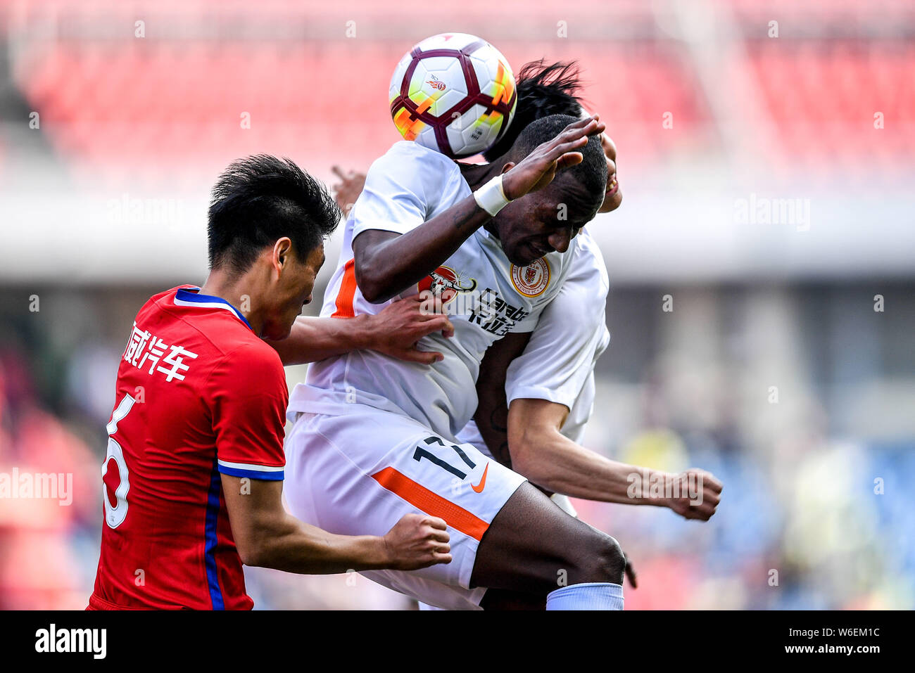 Ecuadorian football player Jaime Ayovi, top, of Beijing Renhe heads the ball to make a pass against a player of Chongqing SWM in their first round mat Stock Photo