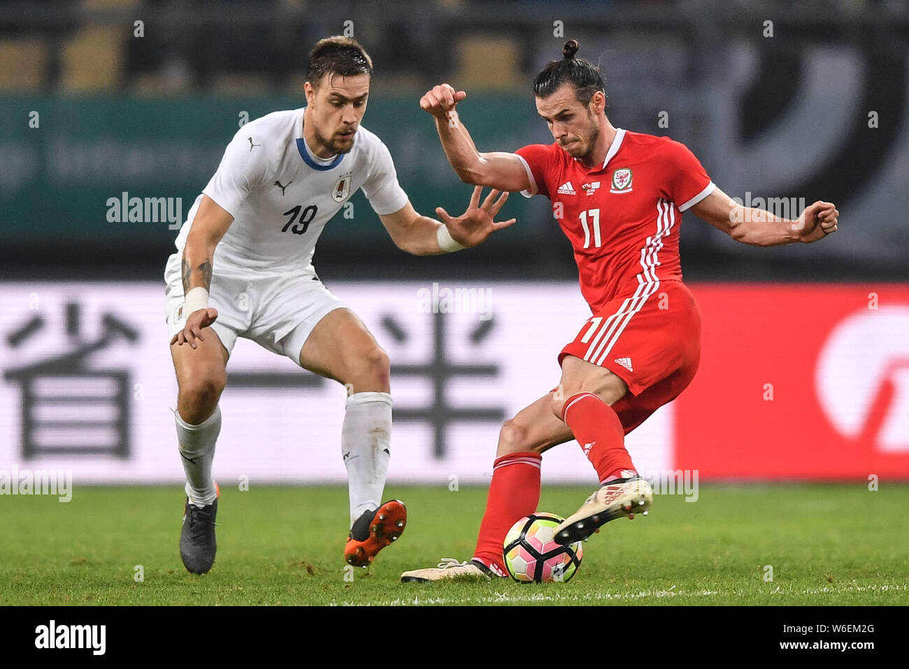 Gareth Bale, right, of Wales national football team kicks the ball to make a pass against Sebastian Coates of Uruguay national football team in their Stock Photo