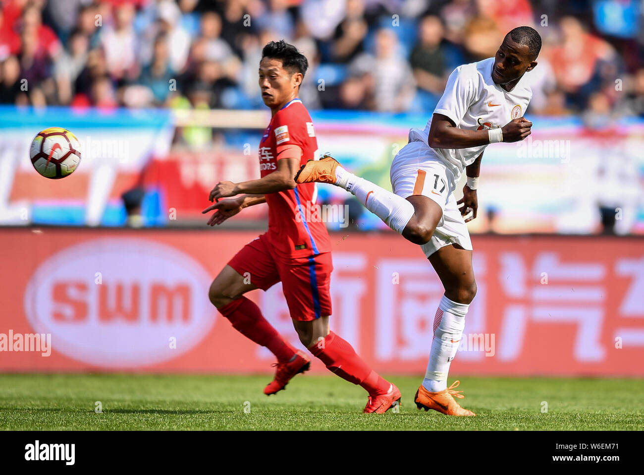 Ecuadorian football player Jaime Ayovi, right, of Beijing Renhe kicks the ball to make a pass against a player of Chongqing SWM in their first round m Stock Photo