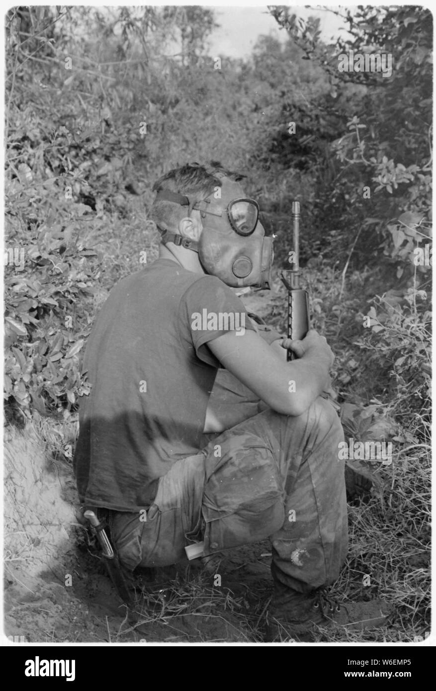 A Marine with the 3nd Battalion, 7th Regiment sits patiently with his gas mask on as he waits to enter a VC tunnel 22 miles south of DaNang, Vietnam. Stock Photo