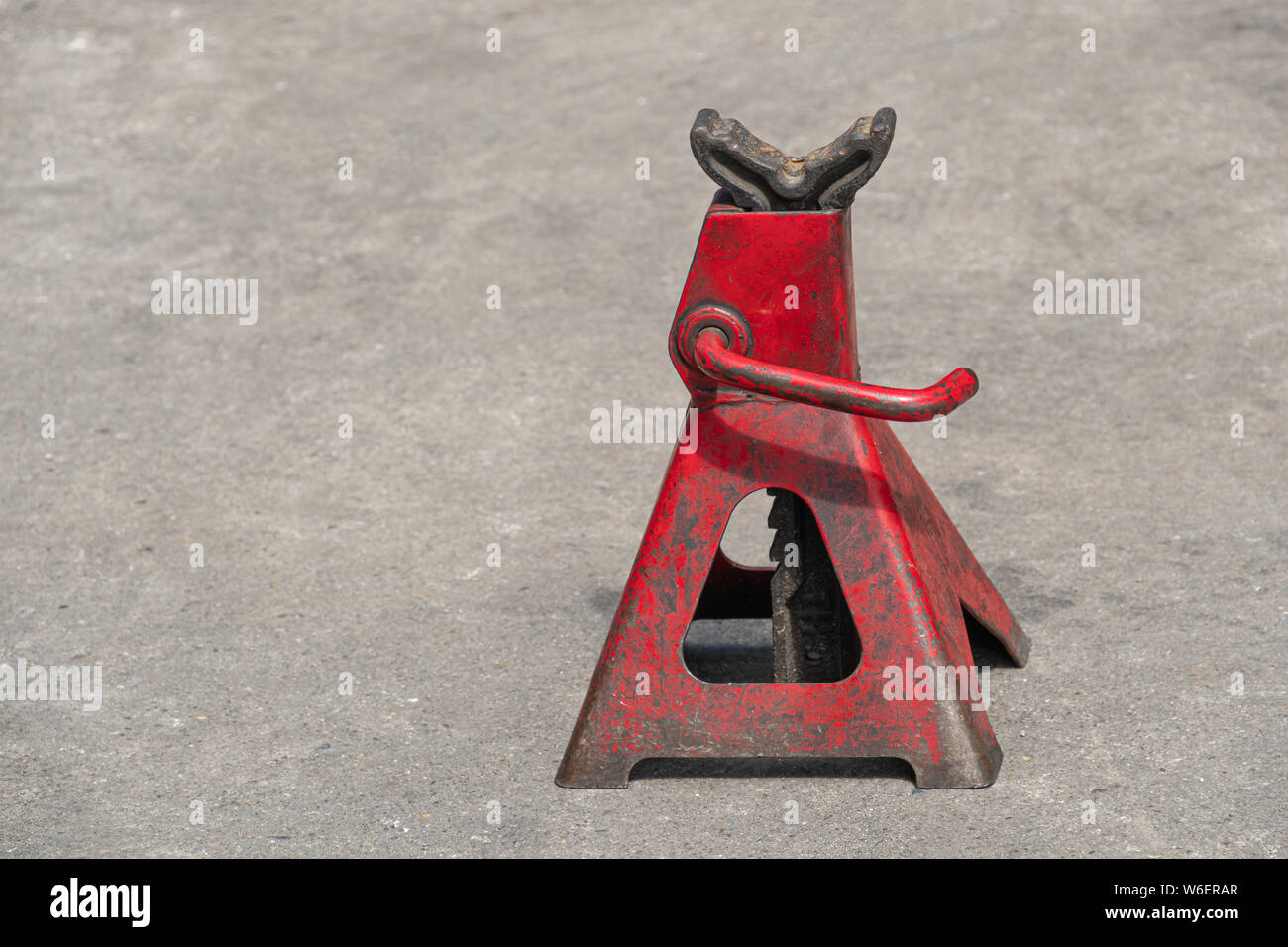 Used red high lift jack stand on the floor. Stock Photo