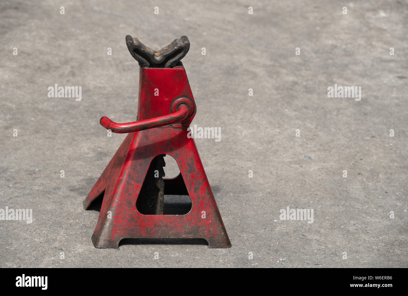 Used red high lift jack stand on the floor. Stock Photo