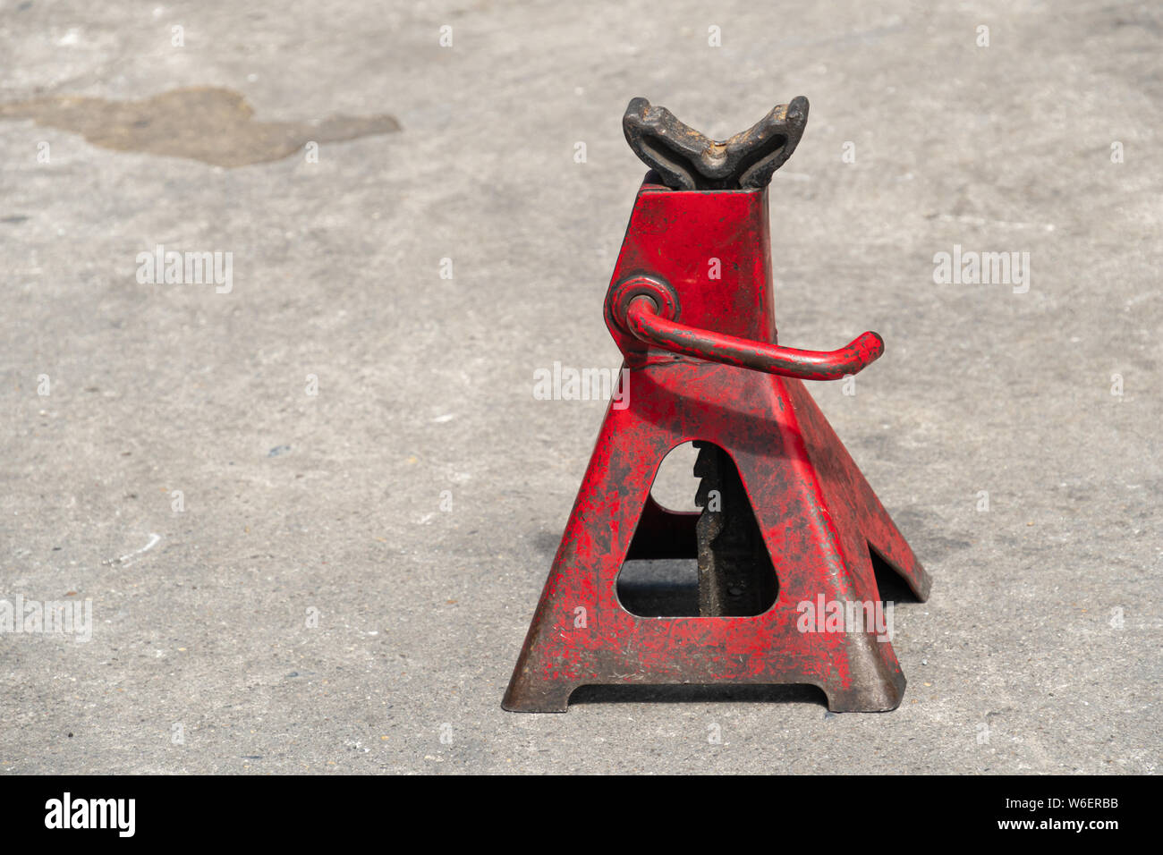 Used red high lift jack stand on the floor. Stock Photo